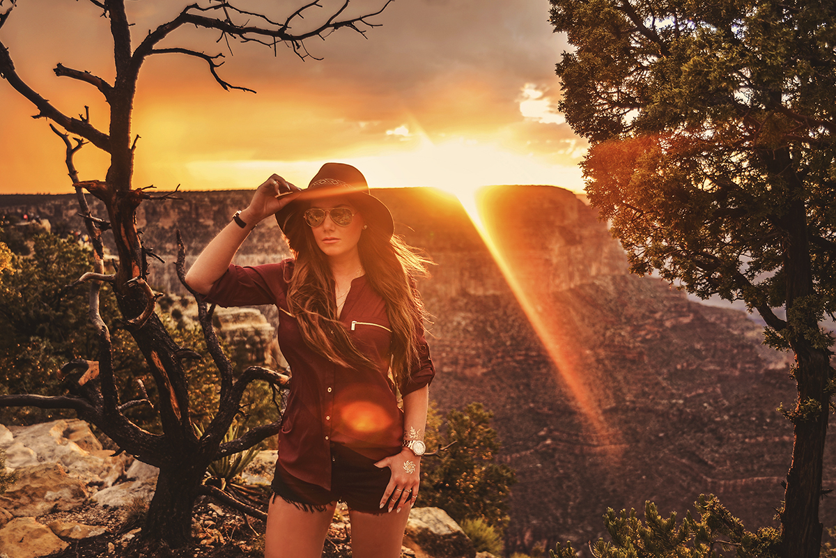 Girl with Ray-Bans and hat standing in Grand Canyon sunset at Mather Point