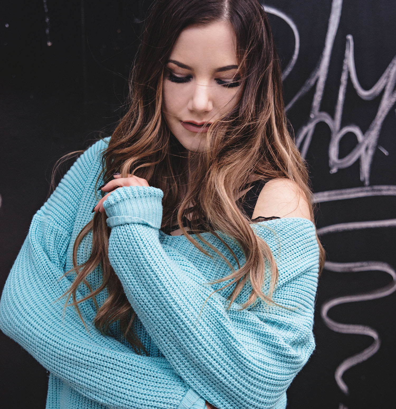 Woman with balayage hair and beach waves +wearing cosy mint green knitted sweater