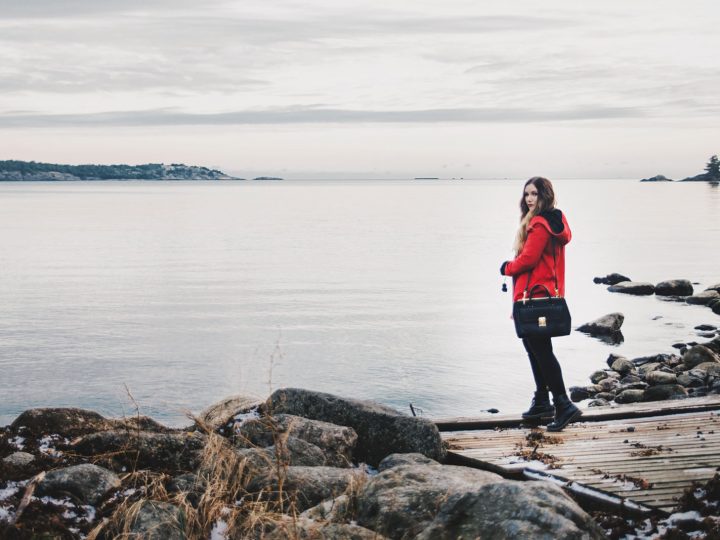 Woman with red coat standing beside a like