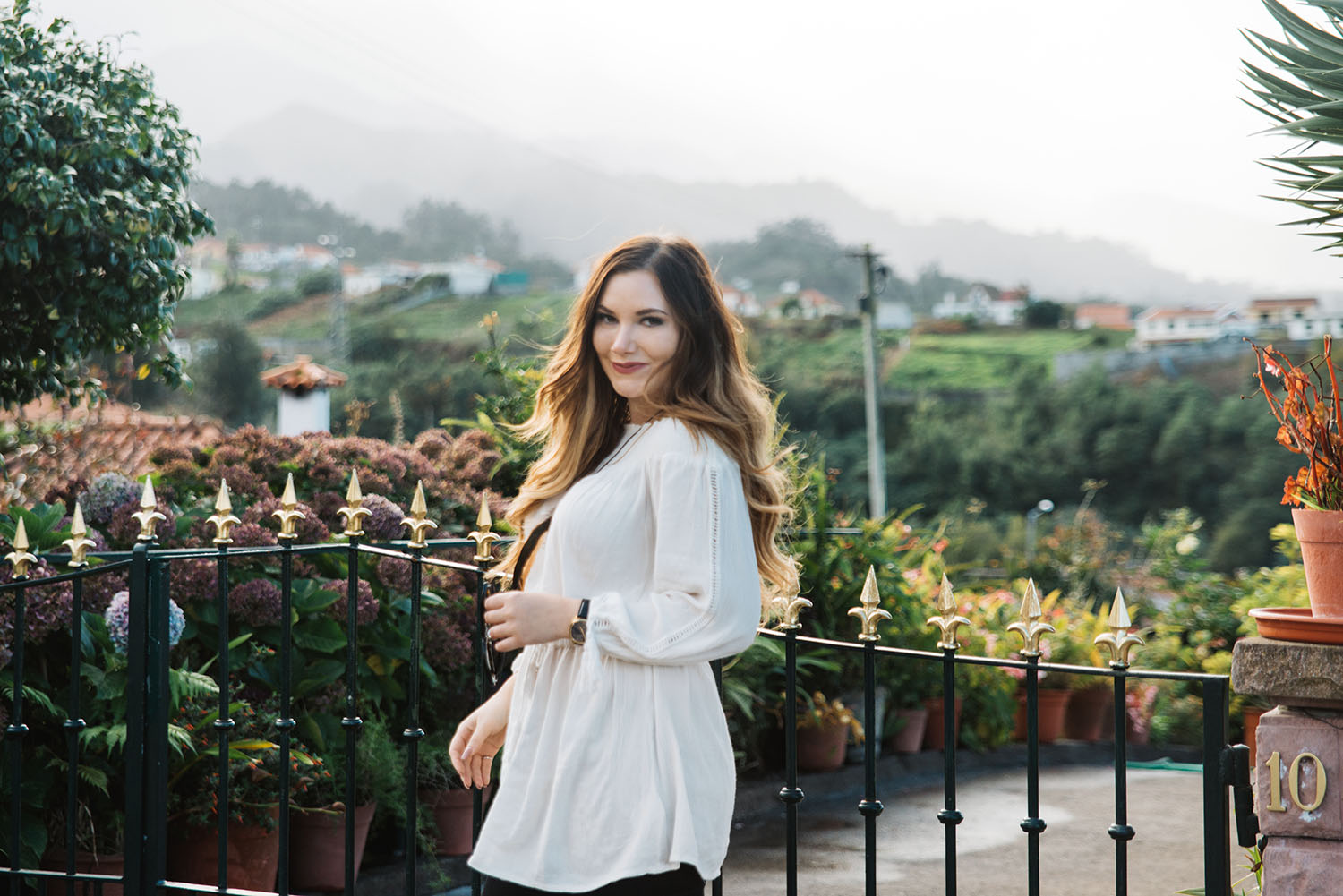 Woman with long hair and white off shoulder standing in sunset in Santana, Madeira