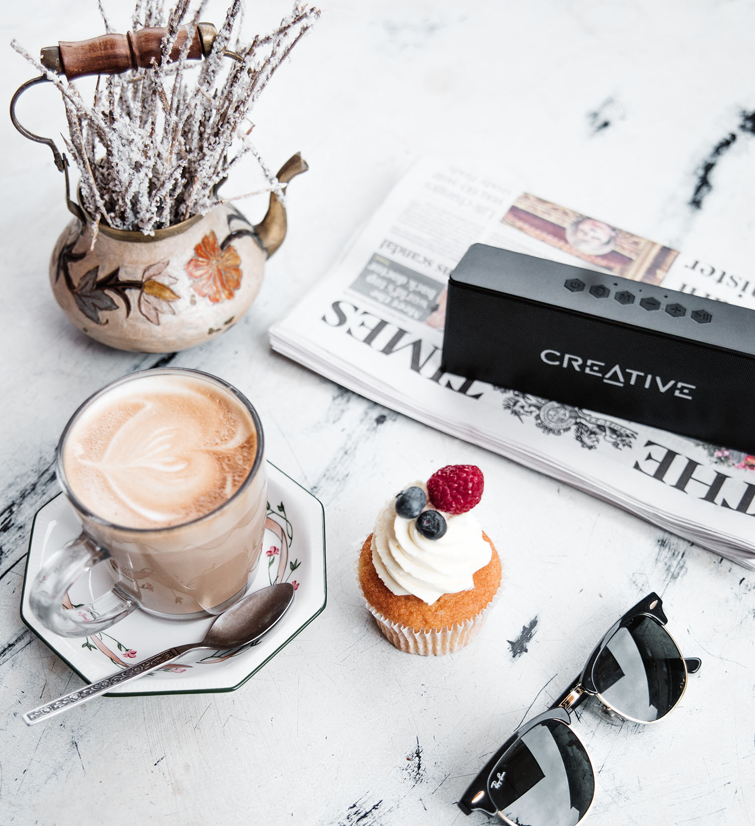 Flatlay with Creative MUVO 2 Bluetooth Speaker, Latte, Ray-Ban & Cupcake