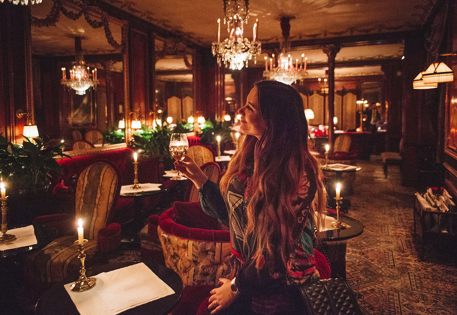 Woman with long hair in beautiful room with a glass of wine at Hotel Costes in Paris