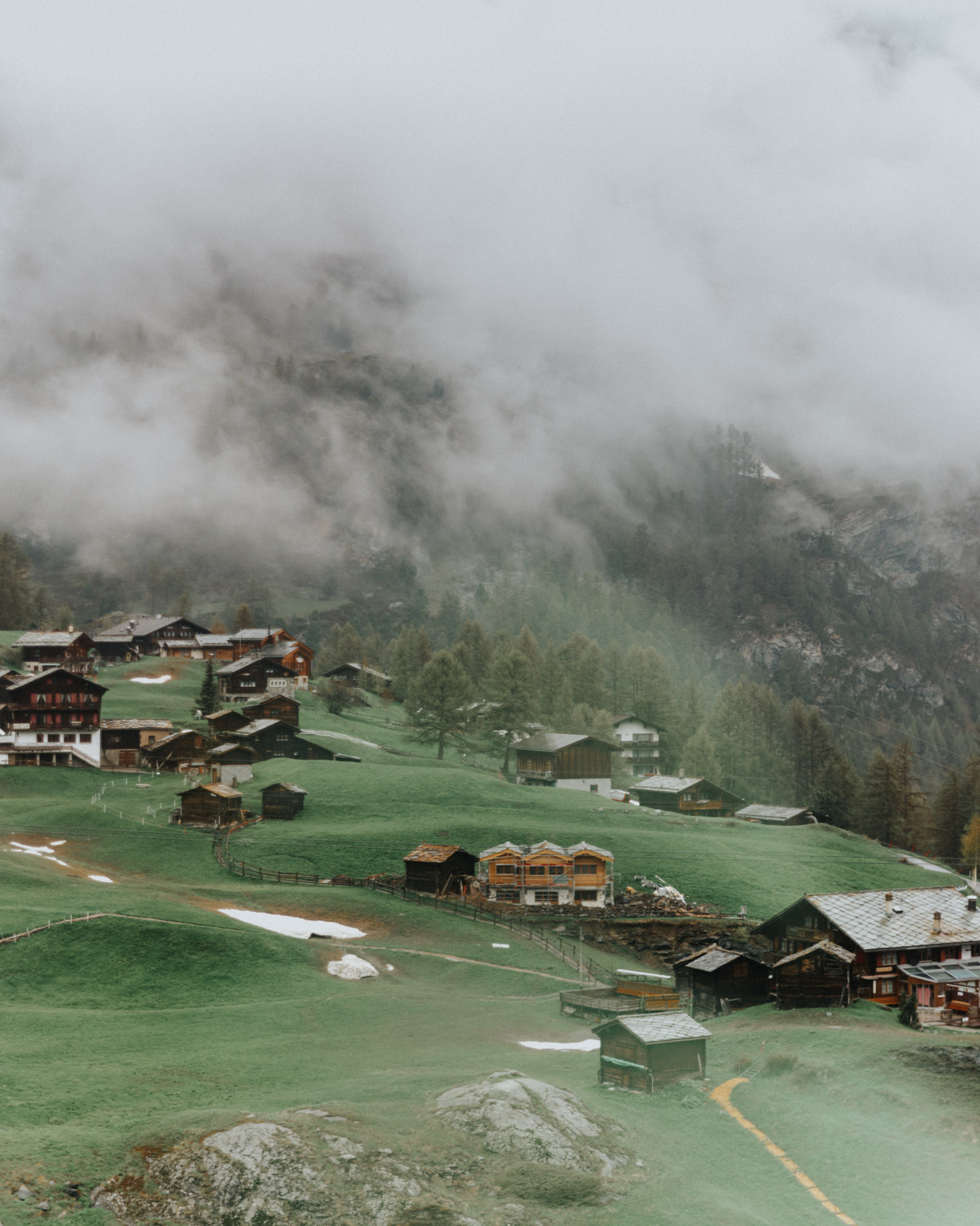 Byn Zermatt bland molnen i Schweiziska alperna 