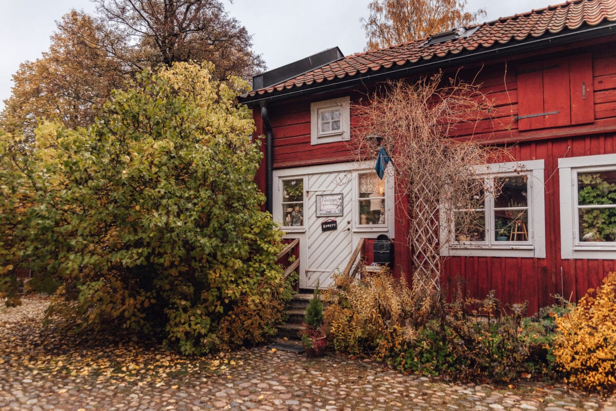 Vintage second hand i rött trähus omgivet av färgglada höstlöv i Wadköping, Örebro