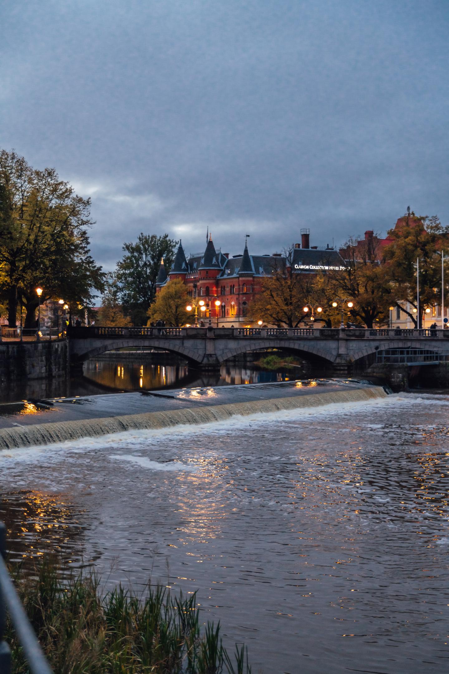 Kvällsbild i Örebro vid Svartån med vackra Clarion Collection Hotel Borgen synlig bakom höstträd