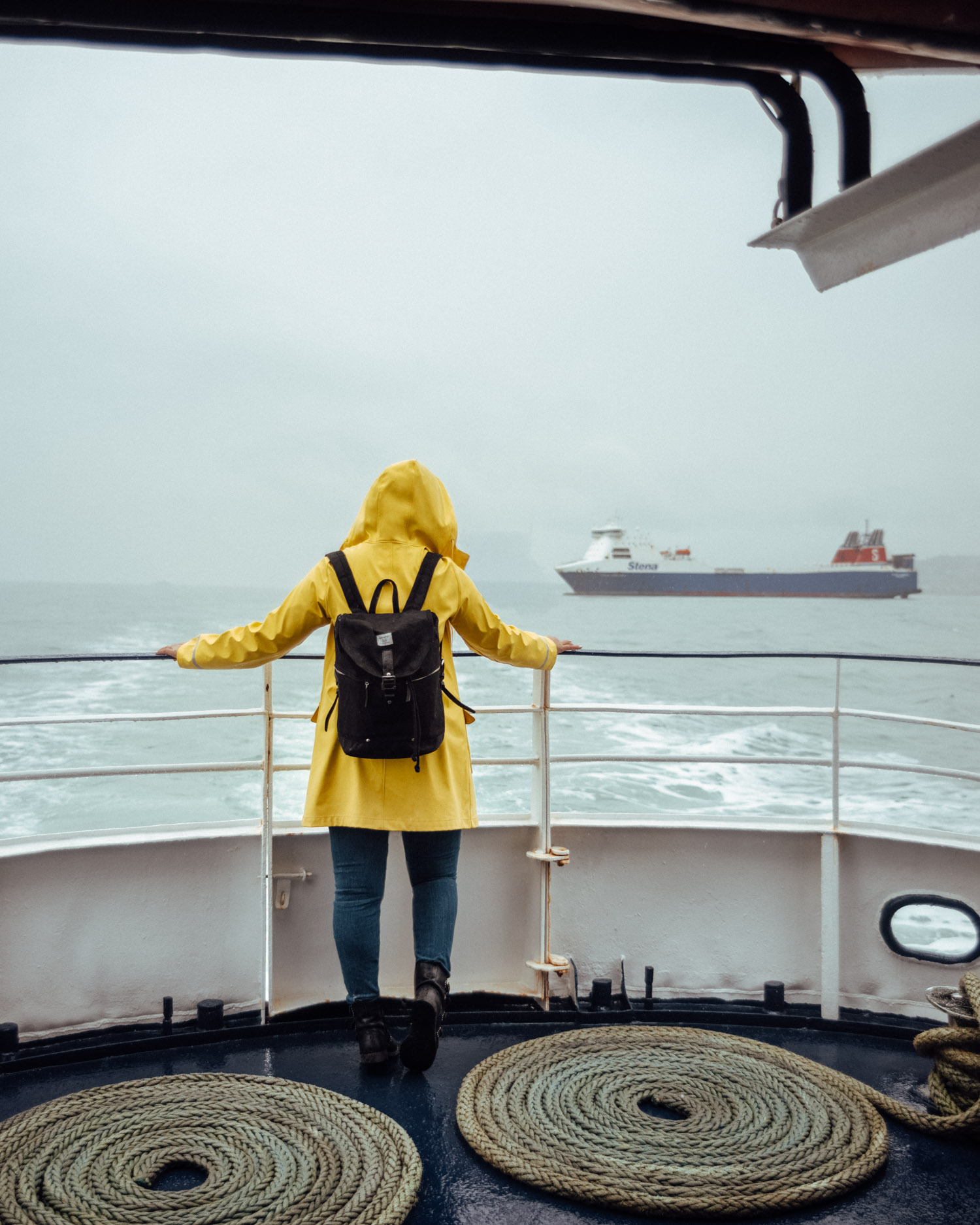 Dublin Bay Cruises to Howth | Woman with yellow raincoat standing on a boat in the rain