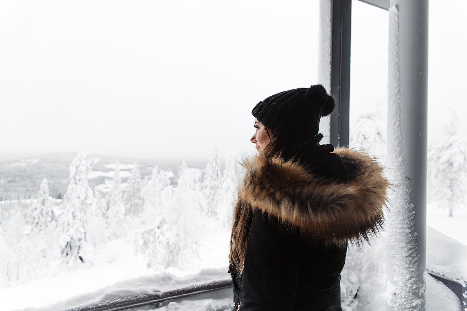 Woman with fake fur coat standing in the winter wonderland Pikku-Syöte